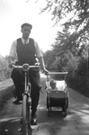 845151 Afbeelding van dhr. Piet Bruinsma die zijn zoontje Johnny in de kinderwagen al fietsend voorttrekt.